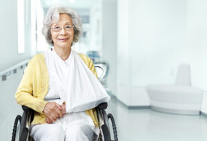 Senior woman in wheelchair and arm sling