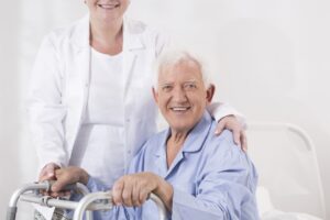 Smiling woman using ALS care tips to help a senior man with a walker, who is also smiling.