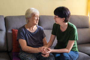 A woman comforts an older woman who is encountering one of the factors that can make Alzheimer’s worse.