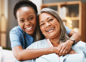 A woman receiving 24-hour care smiles confidently with her caregiver by her side.