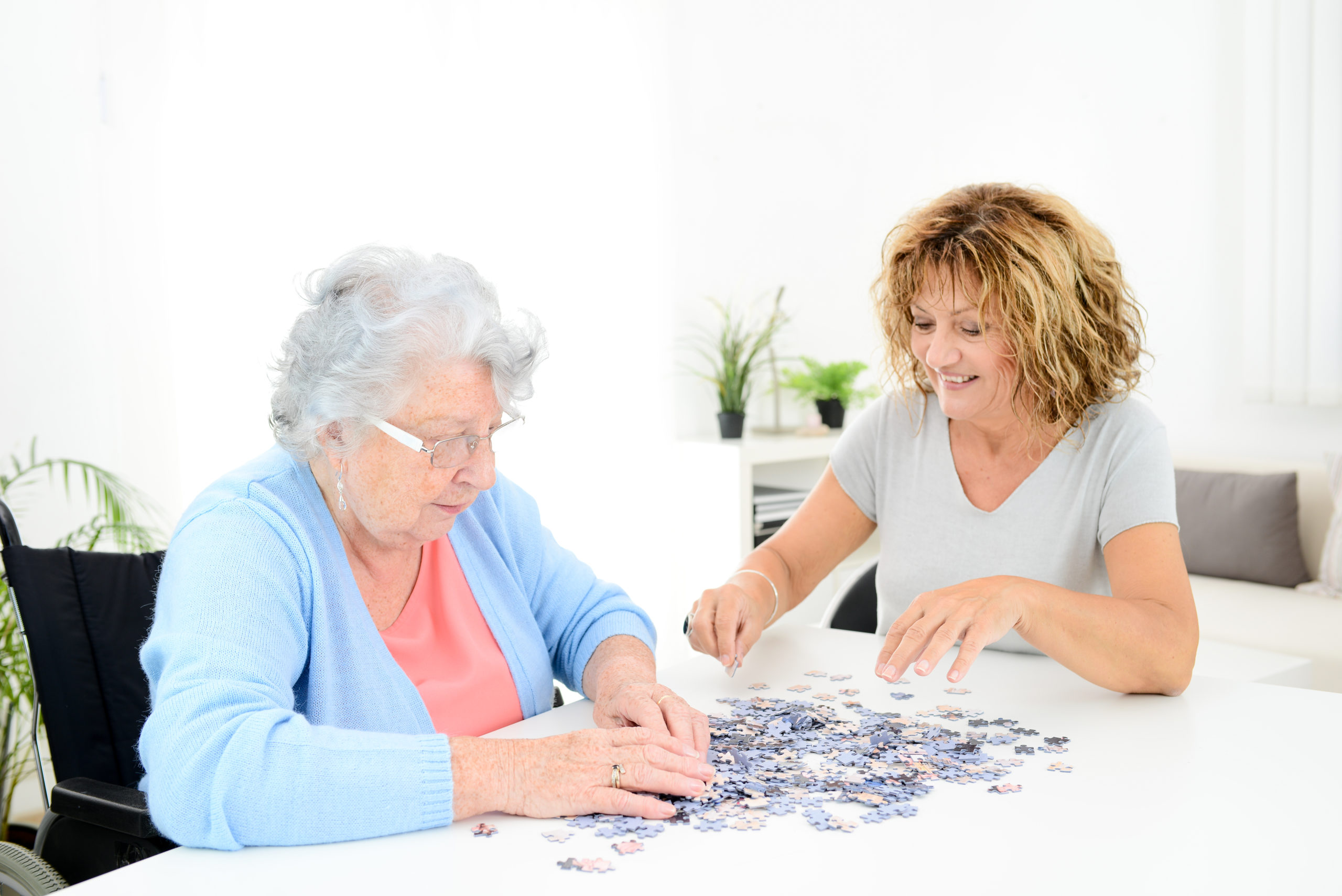 Senior woman and caregiver enjoying a puzzle together