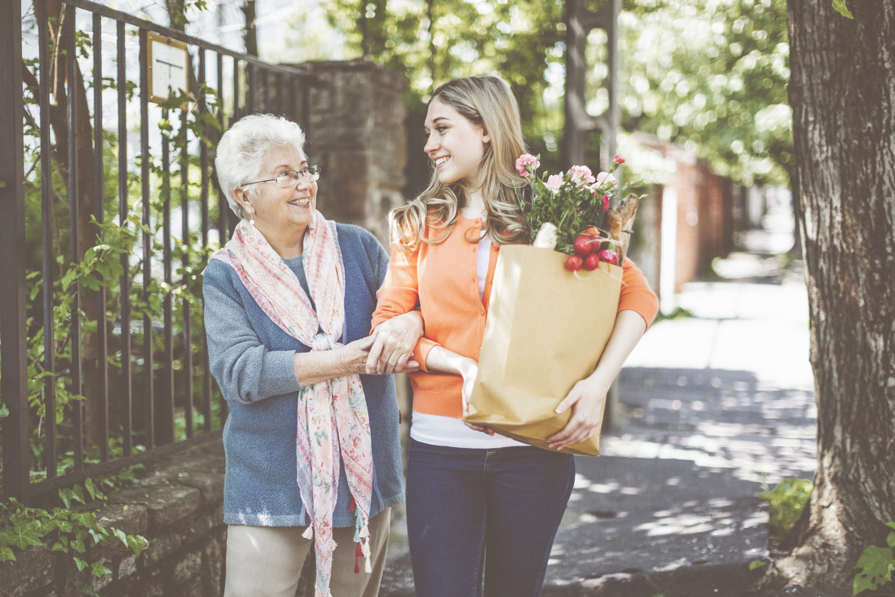 Senior woman and caregiver walking home from grocery store