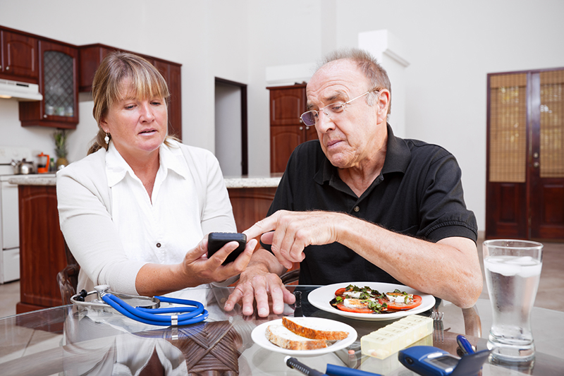A man receiving diabetes care at home checks his blood sugar level.