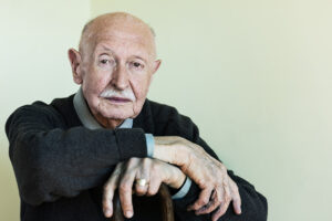 A man whose caregiver prioritizes helping seniors stay independent leans confidently on his cane.