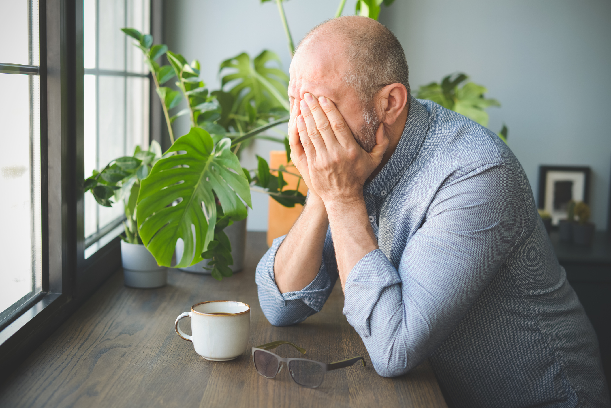 A man struggles with recognizing PTSD symptoms in seniors and rests his head in his hands.